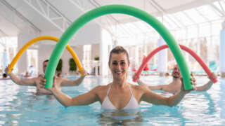 Gesundheitskurs, Gäste mit Schwimmnudeln bei der Gymnastik im Bewegungsbad