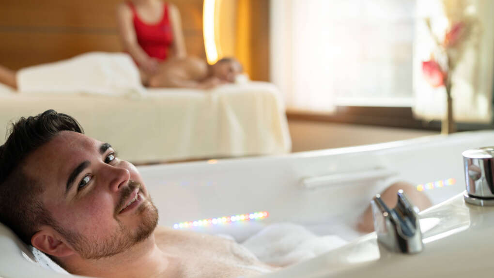 Pärchenwellness einer mit Massage, der andere in der Wanne